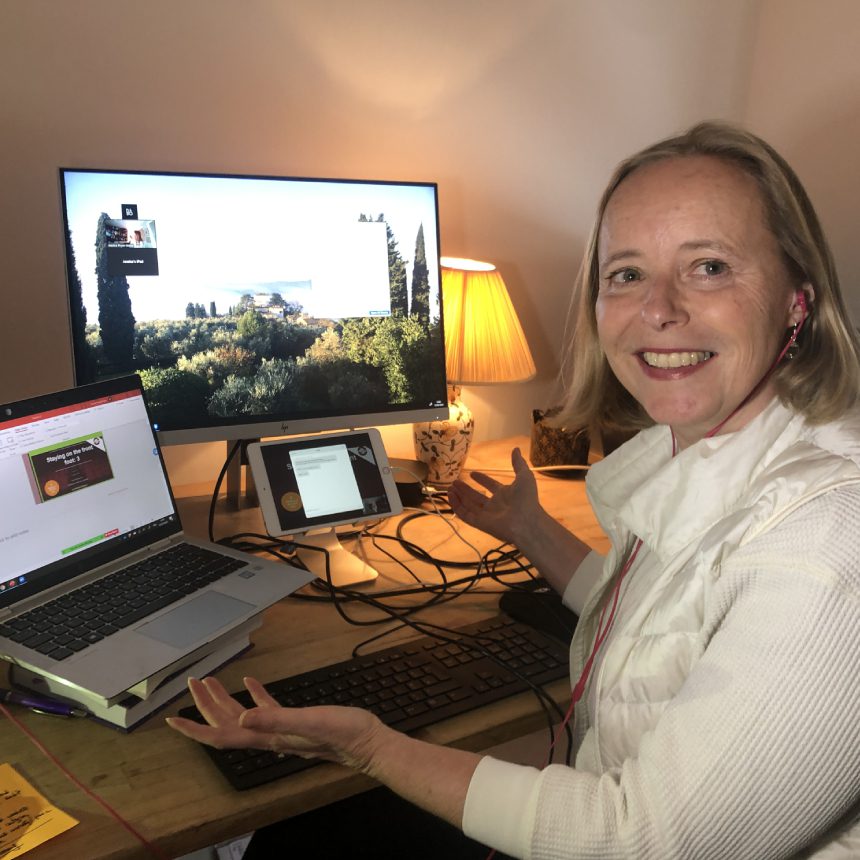 A woman sitting at her desk with two laptops.